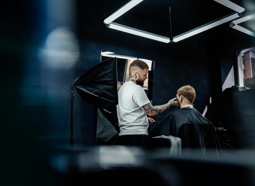 Male haircut with electric razor. Tattooed Barber makes haircut for client at the barber shop by